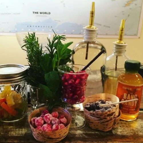 A garnish bar with fresh herbs, cranberries, citrus, syrups and pour spouts